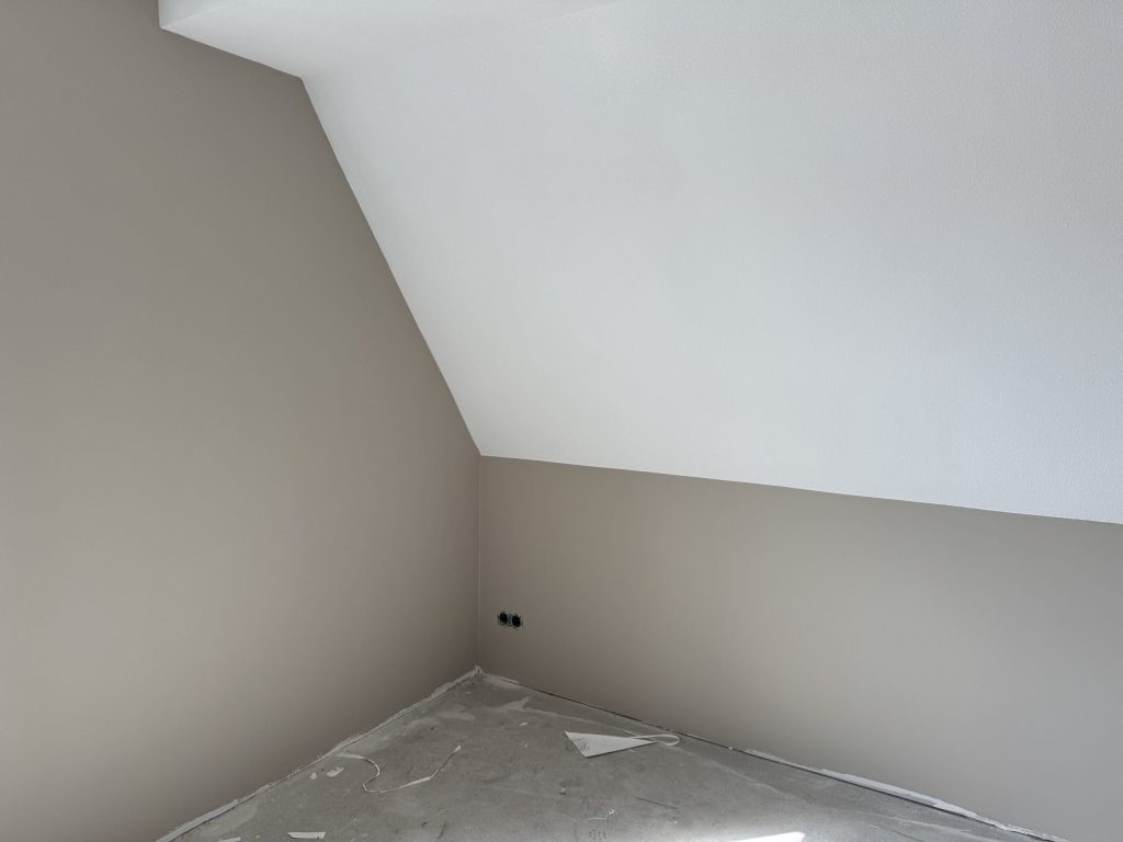 Zolderkamer met een schuine wand in wit en rechte wanden in een warme grijze tint